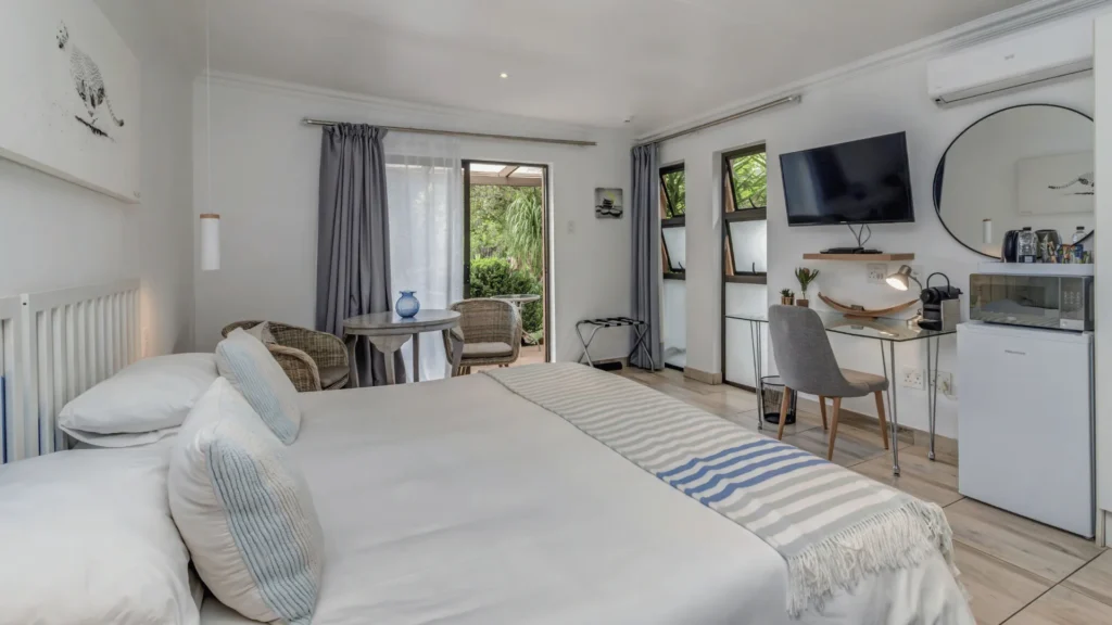Guest room with double bed, desk and doors to a private terrace