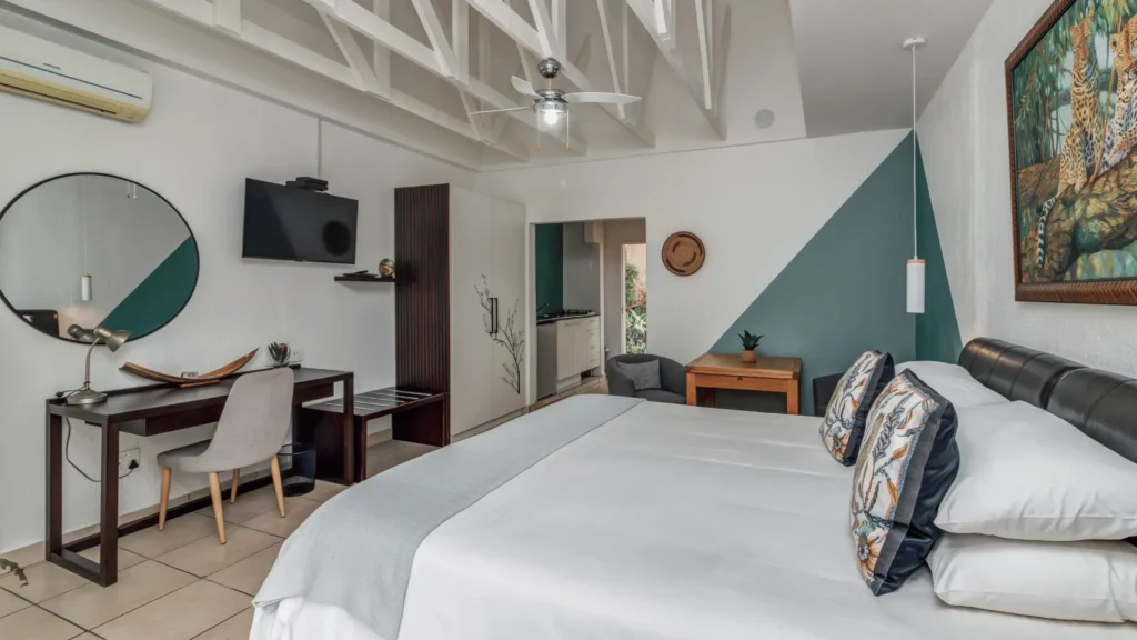 Spacious guest room with a large bed, desk and TV
