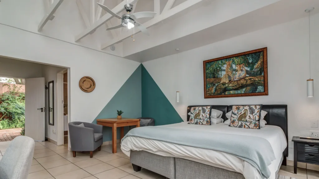 Guest room with a large bed, ceiling fan and small table